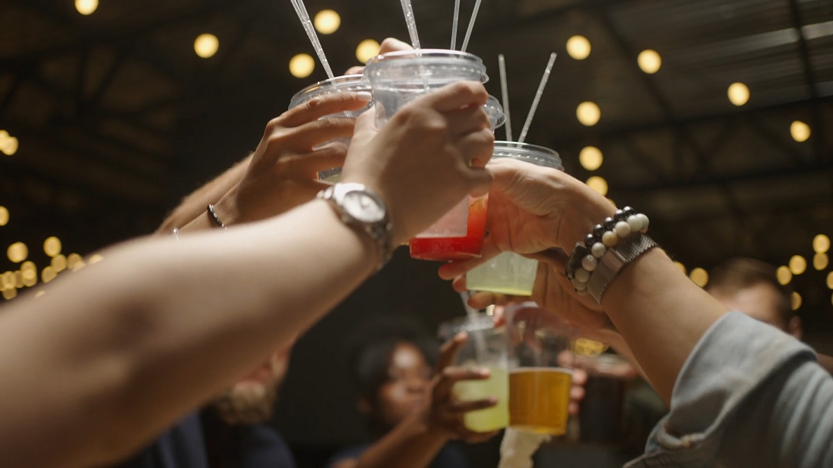 Group of people toasting with colorful drinks in a festive, dimly lit environment