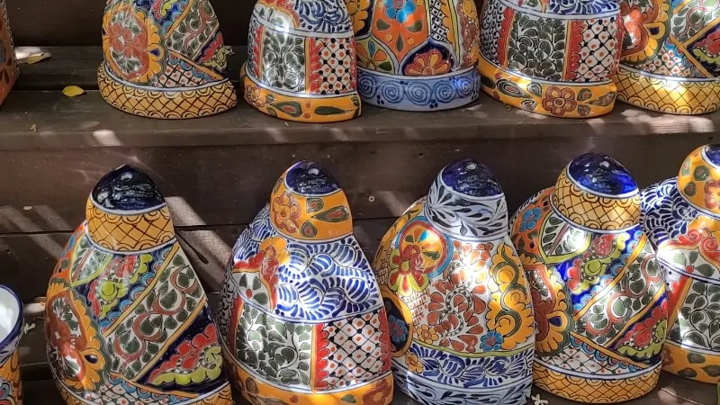 Colorful Talavera Pottery Pieces with Intricate Hand-Painted Patterns Displayed on Wooden Shelves