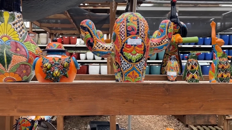 Hand-Painted Talavera Pottery Pieces, Including a Colorful Cactus Sculpture, Displayed on A Wooden Shelf at A Market