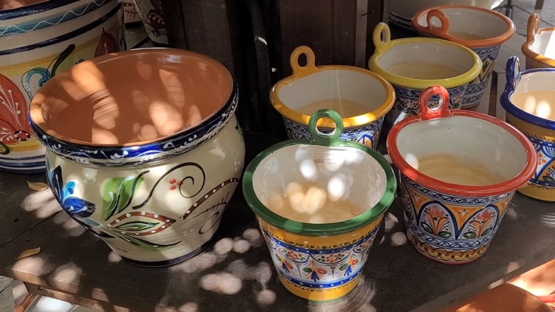 Hand-Painted Talavera Majolica Pots in Various Sizes and Colors Displayed on A Wooden Shelf