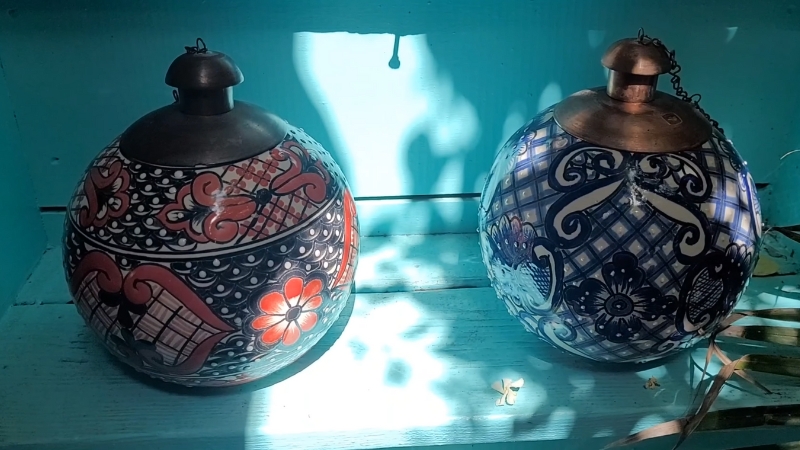 Two hand-painted Talavera pottery lanterns with intricate patterns and metal tops